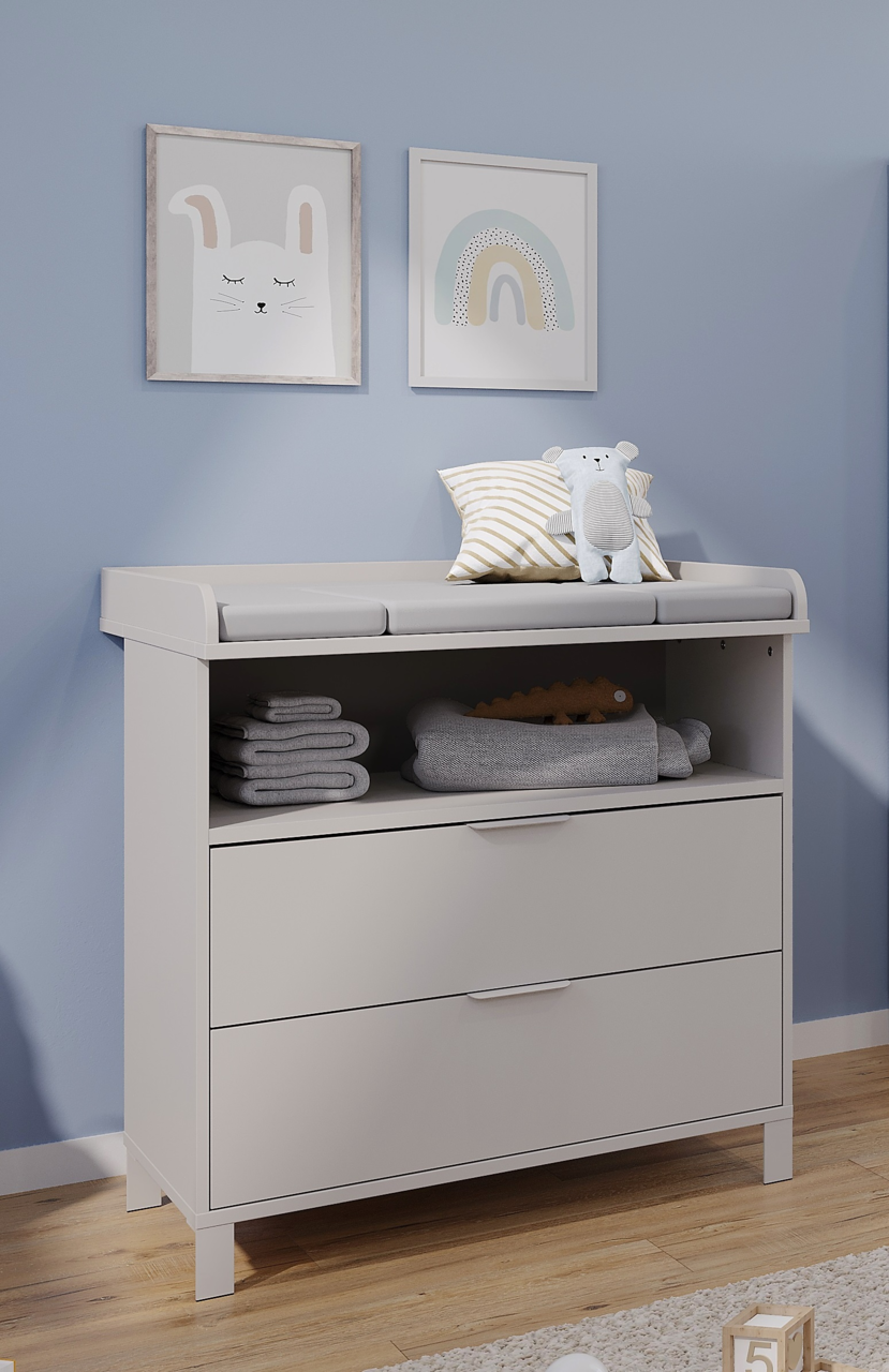 Wickelaufsatz schmal auf einer weißen Kommode mit zwei Schubladen, dekoriert mit einem Kissen und einem Plüschtier, seitliche Perspektive
