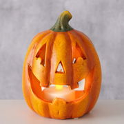 Teelichthalter in Form eines Kürbisses mit geschnitztem Gesicht, frontal fotografiert.