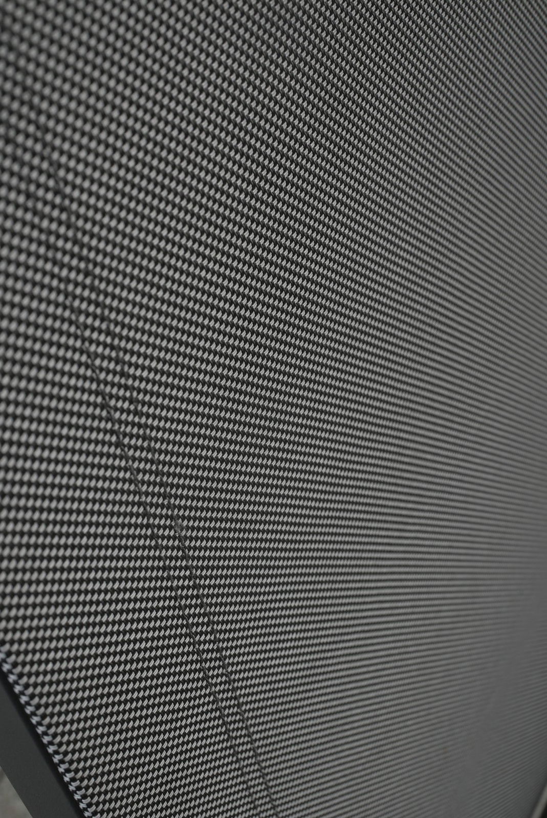 Amatio Gartensessel CHUR Nahaufnahme eines Stapelstuhls mit schwarzem, gewebtem Stoffbezug, von der Seite betrachtet.