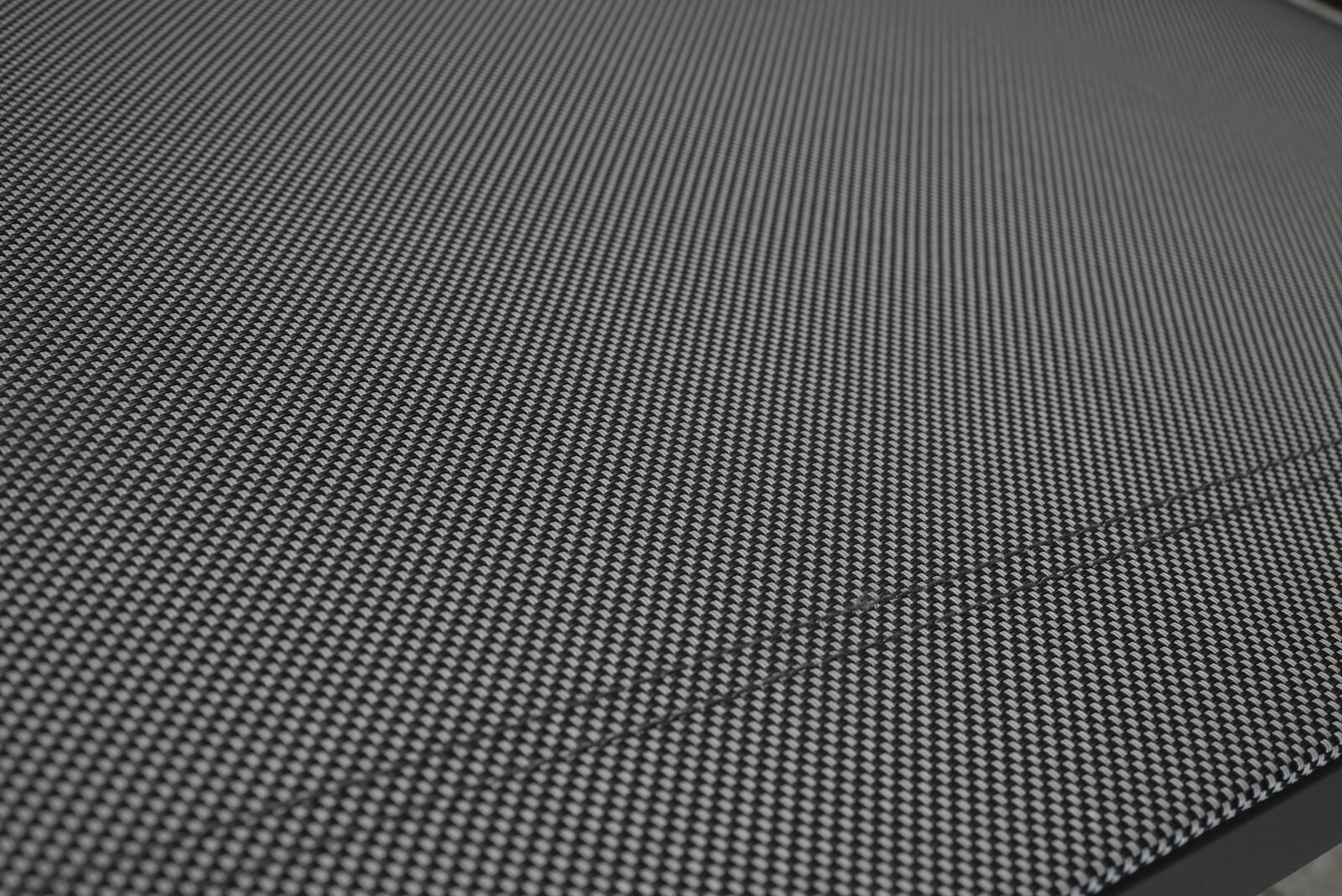 Amatio Gartensessel CHUR Nahaufnahme eines Stapelstuhls mit schwarzem, gewebtem Stoffbezug, von der Seite betrachtet.