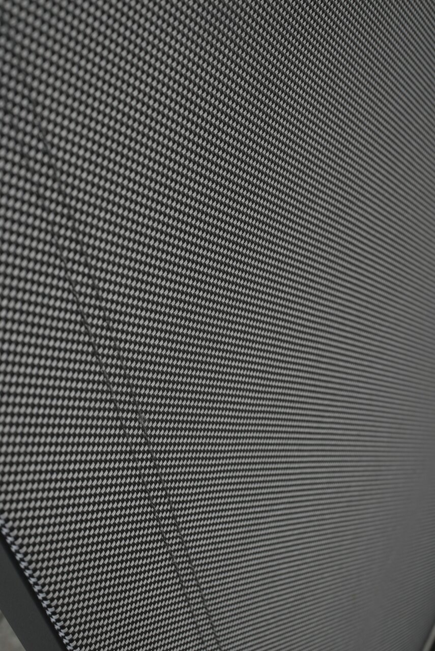 Amatio Gartensessel CHUR Nahaufnahme eines Stapelstuhls mit schwarzem, gewebtem Stoffbezug, von der Seite betrachtet.