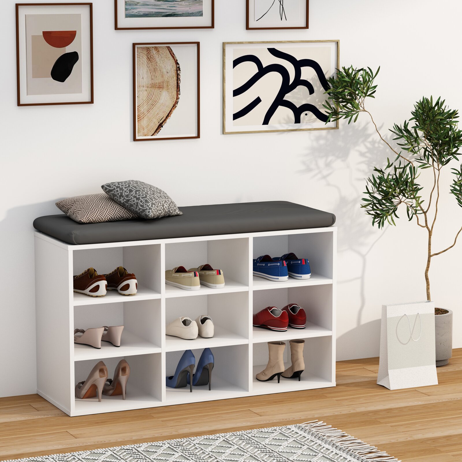 Weißes Schuhregal mit Sitzbank und dunkelgrauem Polster, gefüllt mit Schuhen und zwei Kissen, in modernem Flur-Setting; Perspektive: frontale Ansicht auf Augenhöhe, leicht von links