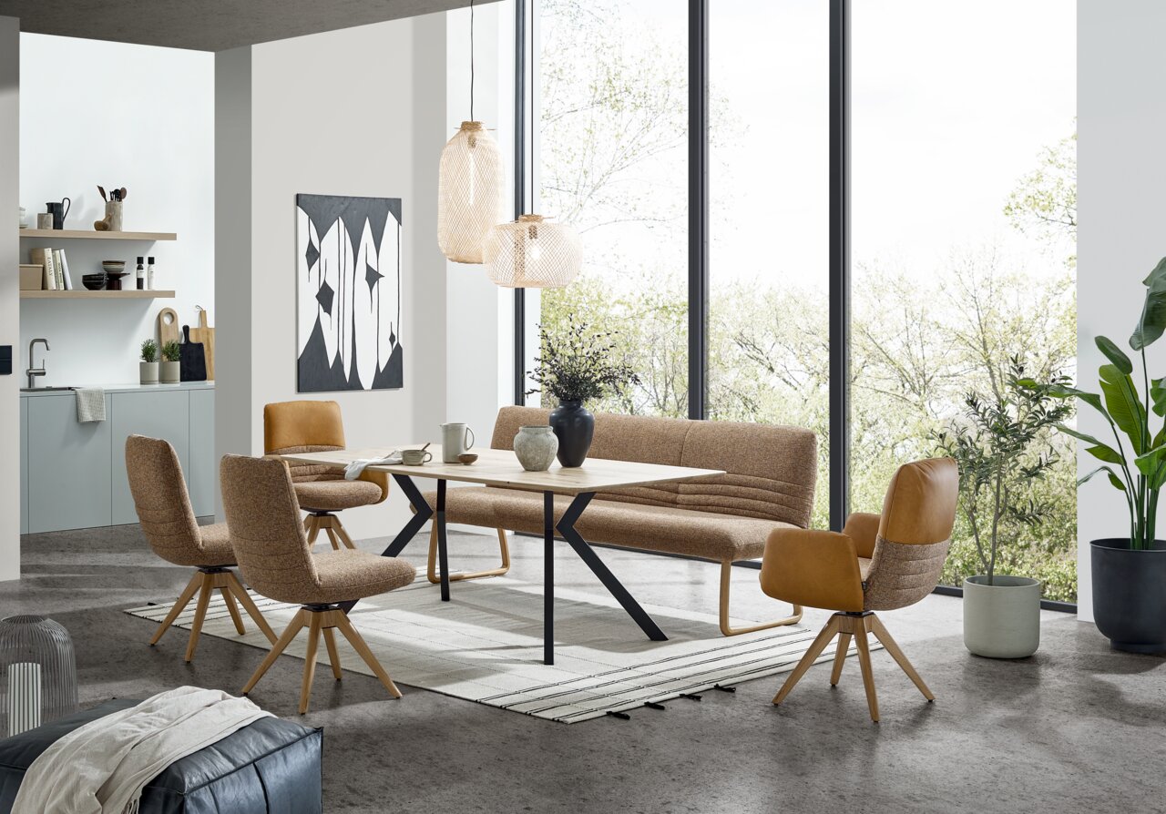 Moderner Esstisch 180x100cm mit Holzplatte und schwarzen Metallbeinen, umgeben von stilvollen Stühlen und einer Bank in einem hellen, offenen Raum mit großen Fenstern. Perspektive: seitlich.