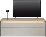 Vooraanzicht van een modern tv-lowboard met ingebouwde ledverlichting, een flatscreen-tv en een tafellamp.