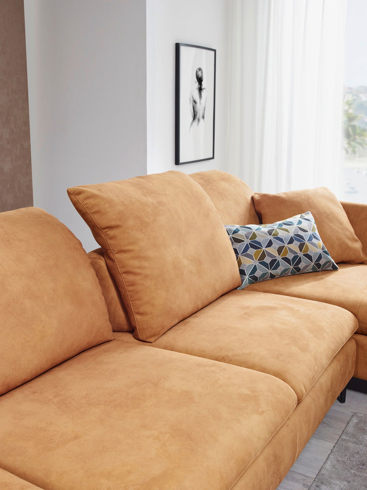 Nahaufnahme einer beigen Longchairkombination mit dekorativem Kissen, seitliche Perspektive.