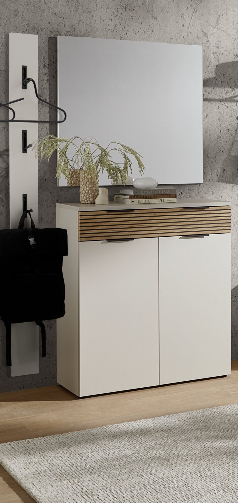 Voleo Garderoben-Set INDO Modernes weißes Sideboard/Schuhschrank mit zwei Türen und Schublade mit Holzlamellenfront, davor frontal leicht schräg fotografiert, mit Spiegel darüber und Garderobenleiste an Betonwand