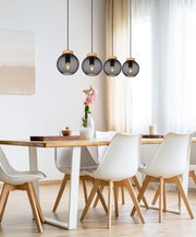 Moderne Hängeleuchte mit schwarzem Gitterdesign und Holzdetails, über einem Esstisch in einem hellen Raum, aus seitlicher Perspektive.