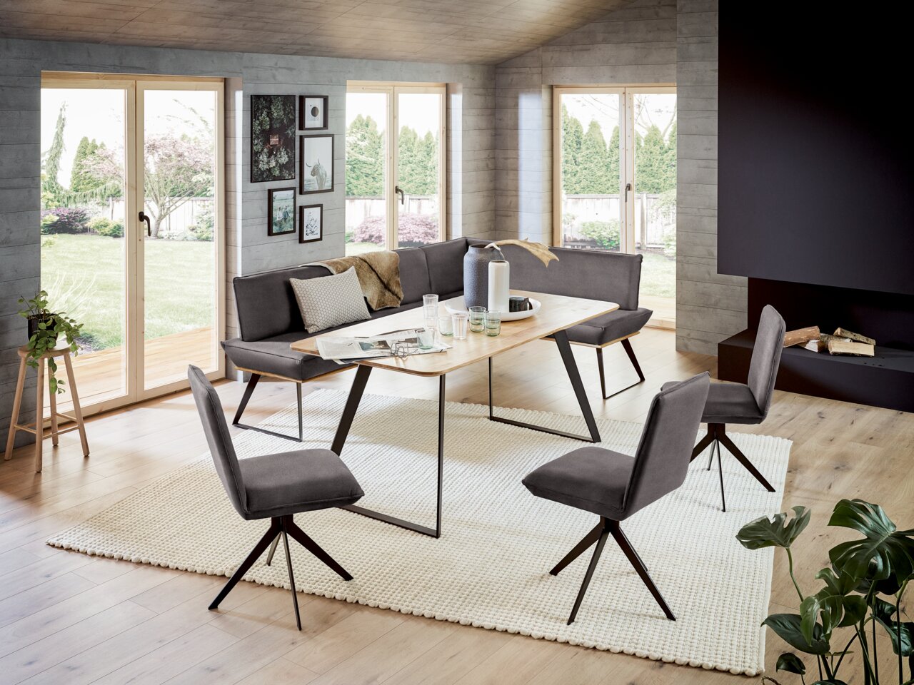 Voleo Eckbank 243x183 cm MALIBU Moderne Eckbank 243x183 cm in einem stilvollen Wohnzimmer mit großen Fenstern, Holzboden und einem eleganten Esstisch, seitliche Perspektive.