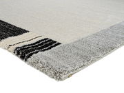 Nahaufnahme eines Teppichs mit grauen und schwarzen Streifen an der Kante, Perspektive von der Seite