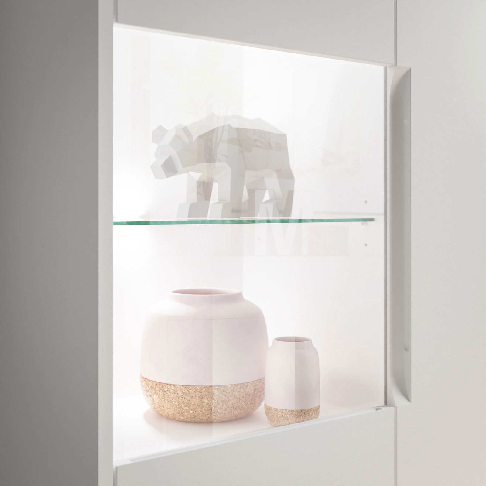 Nahaufnahme eines Highboards mit Glasvitrine, in der ein geometrisches Tiermodell und zwei dekorative Vasen ausgestellt sind.