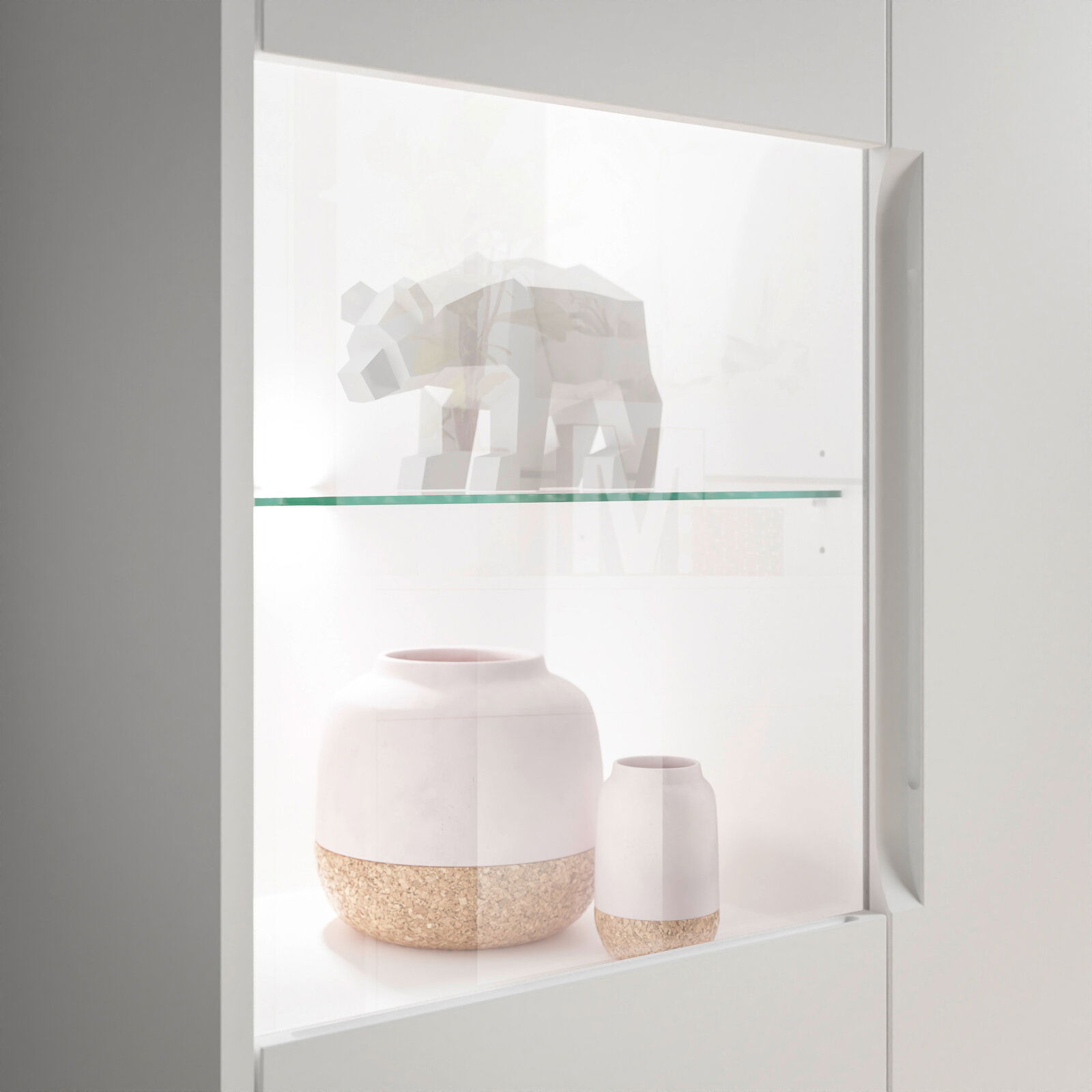 Nahaufnahme eines Highboards mit Glasvitrine, in der ein geometrisches Tiermodell und zwei dekorative Vasen ausgestellt sind.