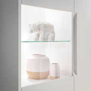 Nahaufnahme eines Highboards mit Glasvitrine, in der ein geometrisches Tiermodell und zwei dekorative Vasen ausgestellt sind.