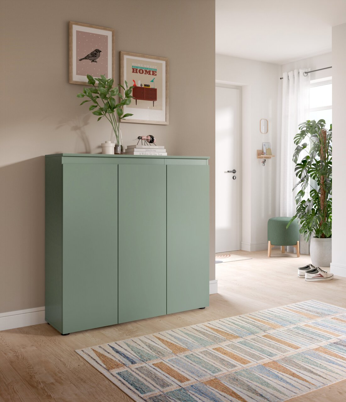 MID.YOU Universalschrank SCARPA Grünes Sideboard mit drei Türen im Flur, dekoriert mit Vase und Bildern an der Wand, fotografiert in leichter Schrägansicht von vorn links.