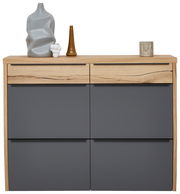 Moderner Hängeschuhschrank in Holzoptik mit grauen Fronten, frontal fotografiert. Dekoriert mit Vasen und Kerzenhalter auf der Oberseite.