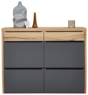 Moderner Hängeschuhschrank in Holzoptik mit grauen Fronten, frontal fotografiert. Dekoriert mit Vasen und Kerzenhalter auf der Oberseite.