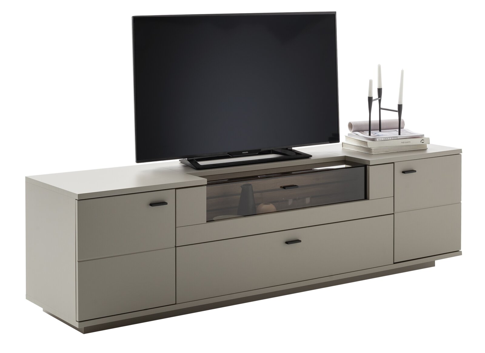 Modern tv-lowboard in taupe/grijs met lades en een vak van getint glas, met tv en decoratie op een witte achtergrond, schuin vooraanzicht