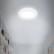 Runde LED-Deckenleuchte Briloner SLIM, leuchtend an der Decke eines modernen Raumes, seitliche Perspektive