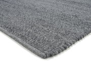 Grauer Handweb Teppich in Nahaufnahme, perspektivisch von der Seite fotografiert.