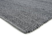 Grauer Handweb Teppich in Nahaufnahme, perspektivisch von der Seite fotografiert.