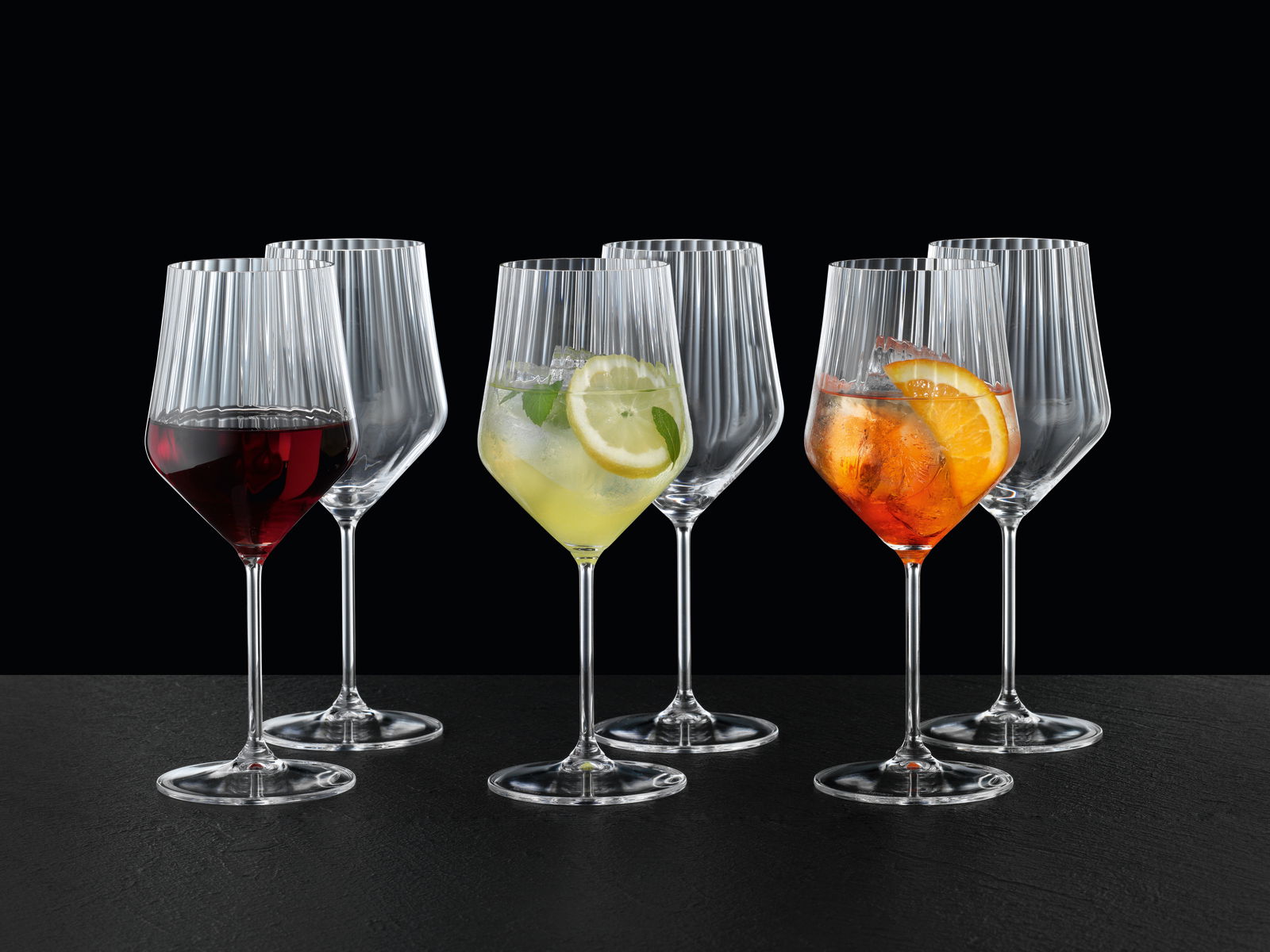 Set aus sechs eleganten Spritz- und Rotweingläsern mit geriffeltem Design, gefüllt mit verschiedenen Getränken, aus frontaler Perspektive fotografiert.
