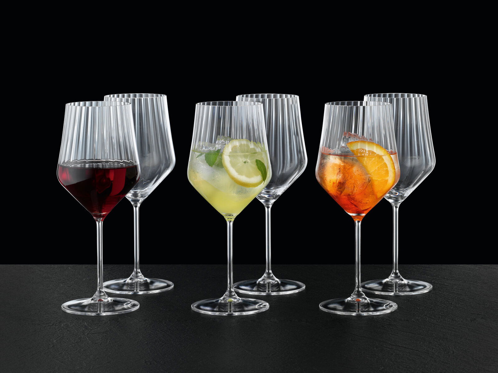 Set aus sechs eleganten Spritz- und Rotweingläsern mit geriffeltem Design, gefüllt mit verschiedenen Getränken, aus frontaler Perspektive fotografiert.
