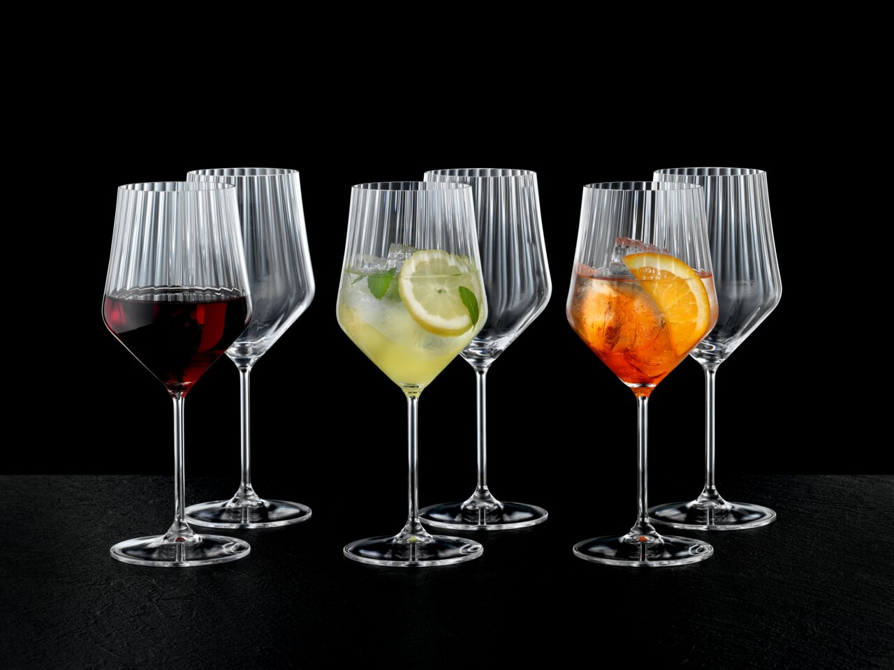 Set aus sechs eleganten Spritz- und Rotweingläsern mit geriffeltem Design, gefüllt mit verschiedenen Getränken, aus frontaler Perspektive fotografiert.