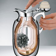 Nahaufnahme einer Kanne mit einem Reinigungsgerät im Inneren, das von einer Hand bedient wird.