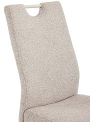 Nahaufnahme eines beige gepolsterten Schwingstuhls mit Rückenlehne, seitliche Perspektive