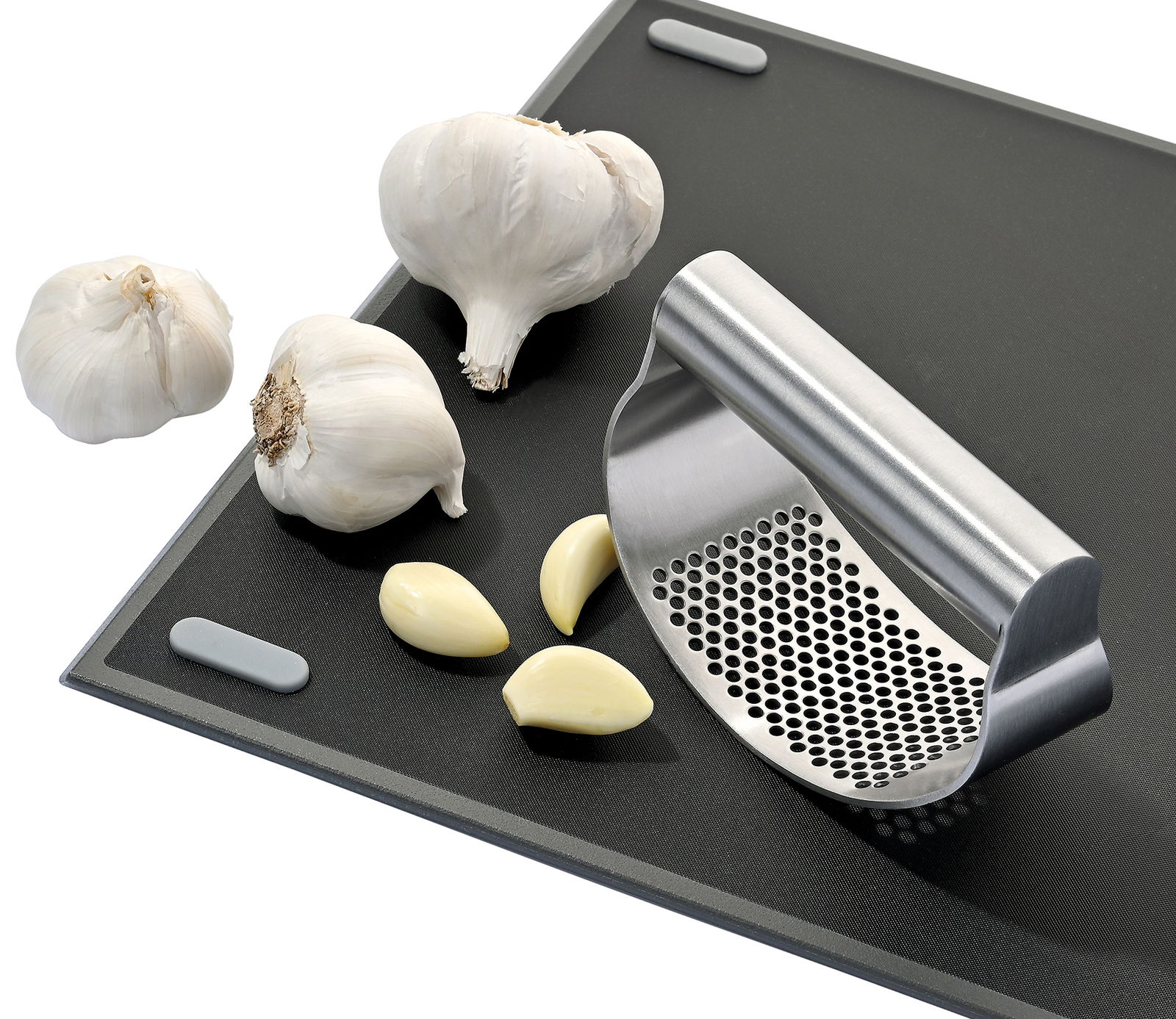Knoblauchpresse SWING aus Edelstahl auf einem Schneidebrett, umgeben von Knoblauchzehen und -knollen, seitliche Perspektive.