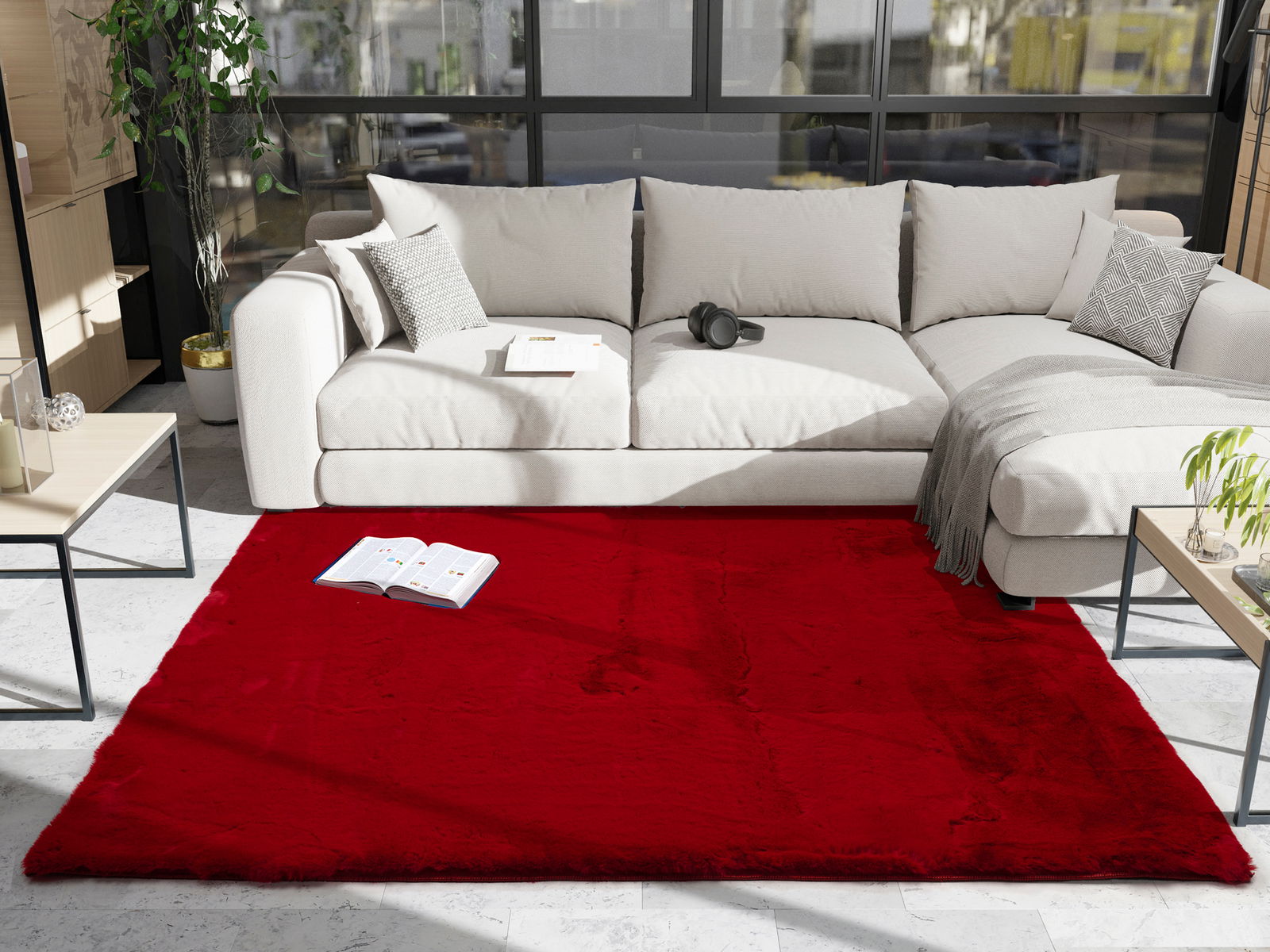 Roter Fellteppich in einem modernen Wohnzimmer, fotografiert aus der Vogelperspektive, vor einem beigen Sofa mit Kissen und einer Decke.