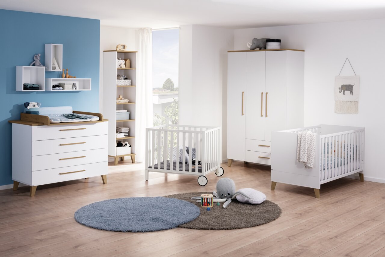 Paidi Wickelaufsatz OSCAR Helles Kinderzimmer mit Wickelaufsatz auf einer weißen Kommode, umgeben von einem Gitterbett, einem Kleiderschrank und einem Regal. Perspektive von vorne.