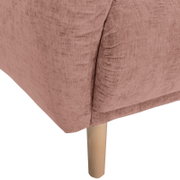 Nahaufnahme einer rosafarbenen Sofaecke mit Holzbein, Perspektive von der Seite.