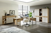 Moderne Büroumgebung mit Winkelschreibtisch, Rollcontainer und Aktenschränken in heller Holzoptik, seitliche Perspektive.