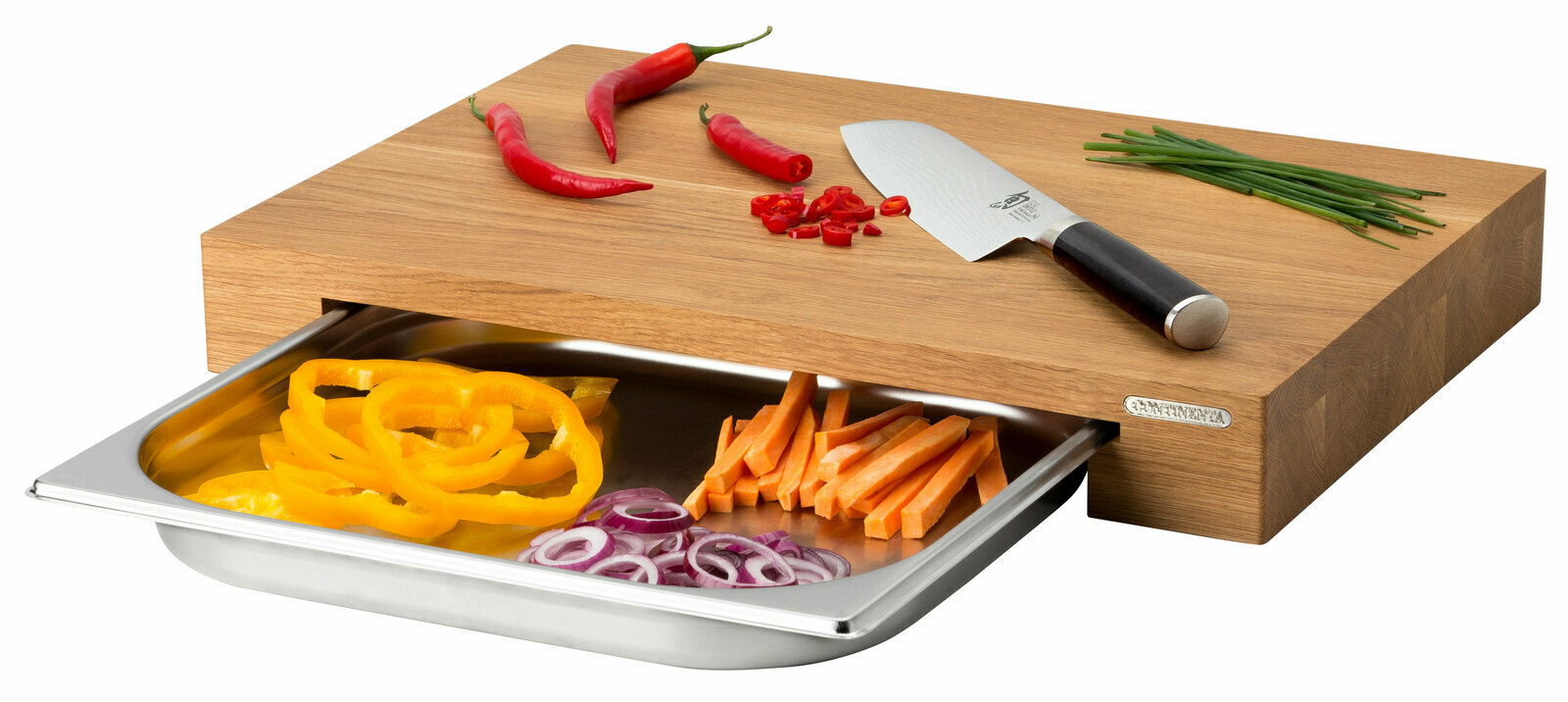 Multifunktionsbrett mit Schublade, darauf liegen rote Chilischoten, ein Messer und Schnittlauch. Die Schublade ist mit geschnittenem Gemüse gefüllt. Perspektive von schräg oben.