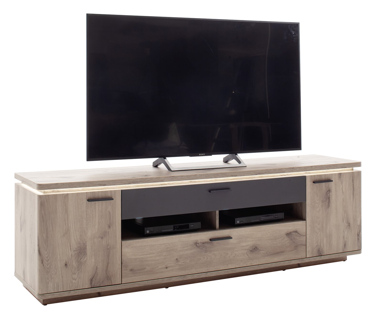 Modernes TV-Lowboard in heller Holzoptik mit schwarzen Fronten, offenen Gerätefächern und Griffen, frontal in leichter Schrägansicht von vorn fotografiert, mit Fernseher auf der Oberplatte.