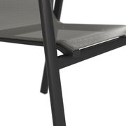 Nahaufnahme eines Stapelstuhls mit schwarzem Metallrahmen und grauer Sitzfläche, seitliche Perspektive