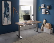 Moderner E-Schreibtisch in einem stilvollen Büro mit blauer Wand, seitliche Perspektive. Der Schreibtisch hat eine Holzoberfläche und silberne Beine, ausgestattet mit einem Computer und Schreibtischlampe.