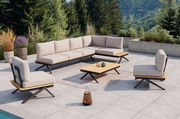 Moderne Loungegarnitur auf einer Terrasse mit Blick auf bewaldete Berge, bestehend aus einem Ecksofa, zwei Sesseln und einem Couchtisch, alle mit hellen Polstern und Holzdetails.