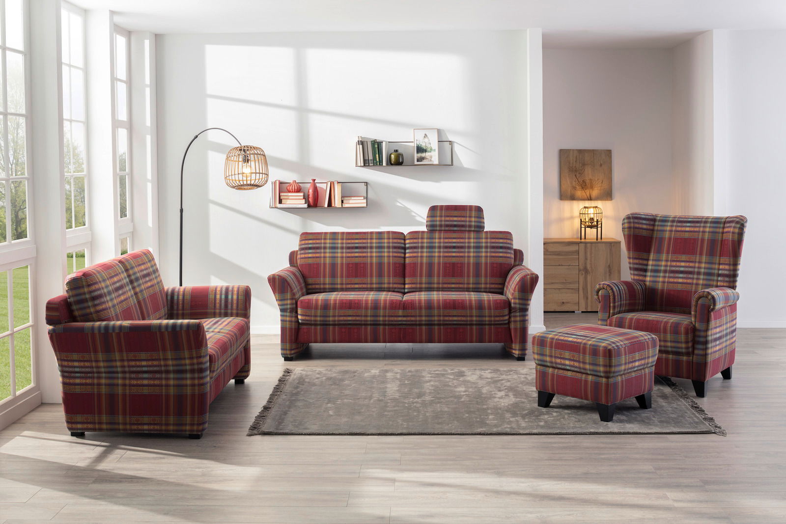 Wohnzimmer mit kariertem Sofa-Set bestehend aus einem 3er-Sofa, einem 2er-Sofa, einem Ohrensessel und einem Hocker, aus der Frontalperspektive fotografiert.