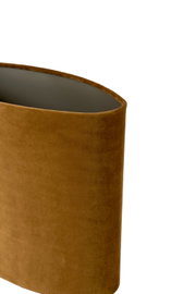 Close-up in schuin bovenaanzicht van een cilindervormige lampenkap met okerbruine fluwelen bekleding en donkere binnenzijde