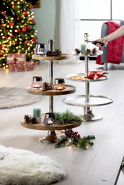 Etagere aus Aluminium mit drei Ebenen, dekoriert mit Kerzen und Tannenzapfen, im weihnachtlich geschmückten Wohnzimmer, seitliche Perspektive