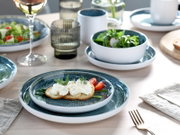 Serviesset van 16-delig, ijsblauw, bestaande uit borden en schalen in een elegant ontwerp, gefotografeerd van bovenaf op een gedekte tafel.