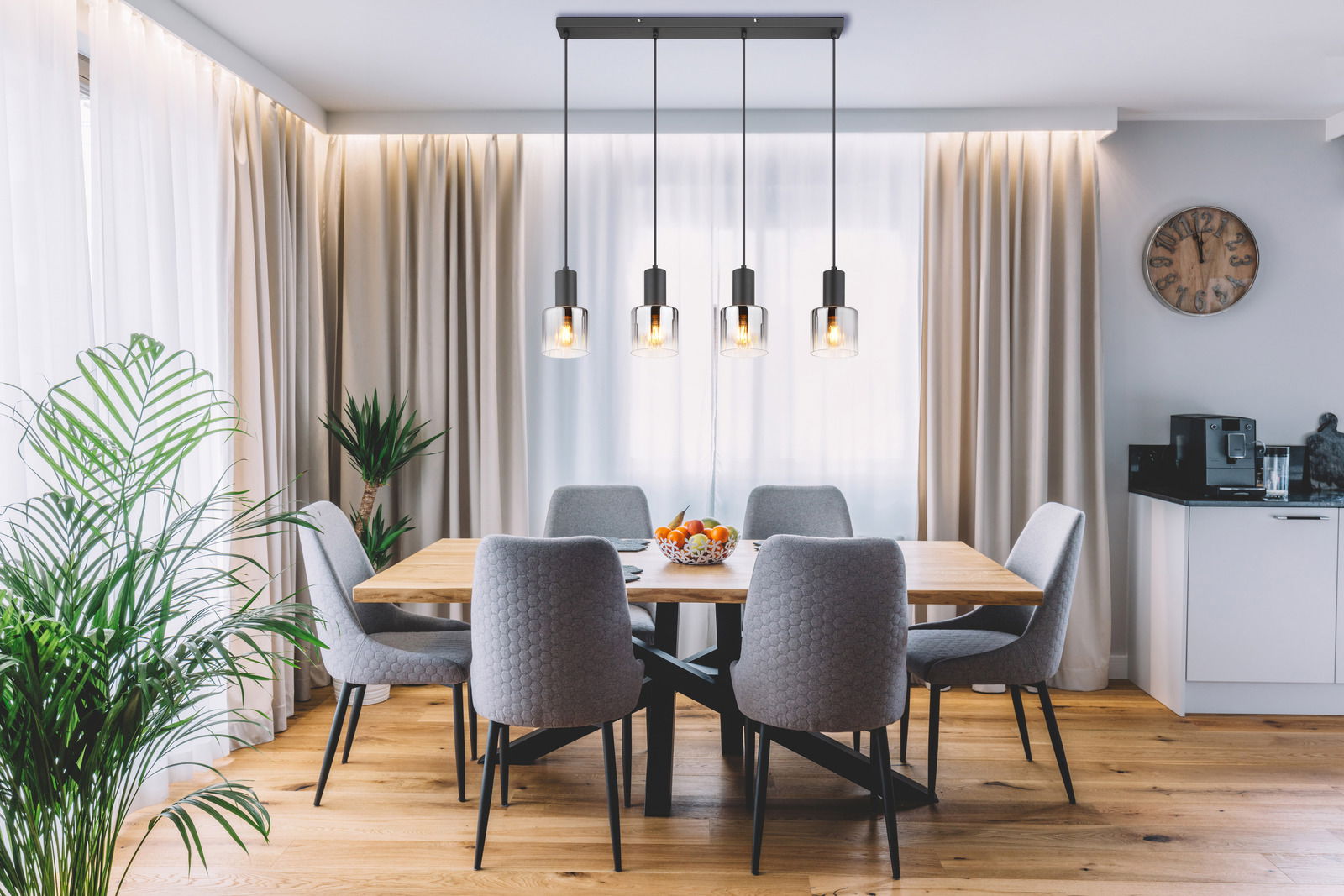 Moderne Hängeleuchte mit vier Glühbirnen über einem Esstisch in einem stilvoll eingerichteten Esszimmer, seitliche Perspektive.