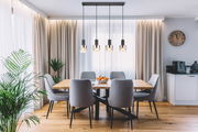 Moderne Hängeleuchte mit vier Glühbirnen über einem Esstisch in einem stilvoll eingerichteten Esszimmer, seitliche Perspektive.