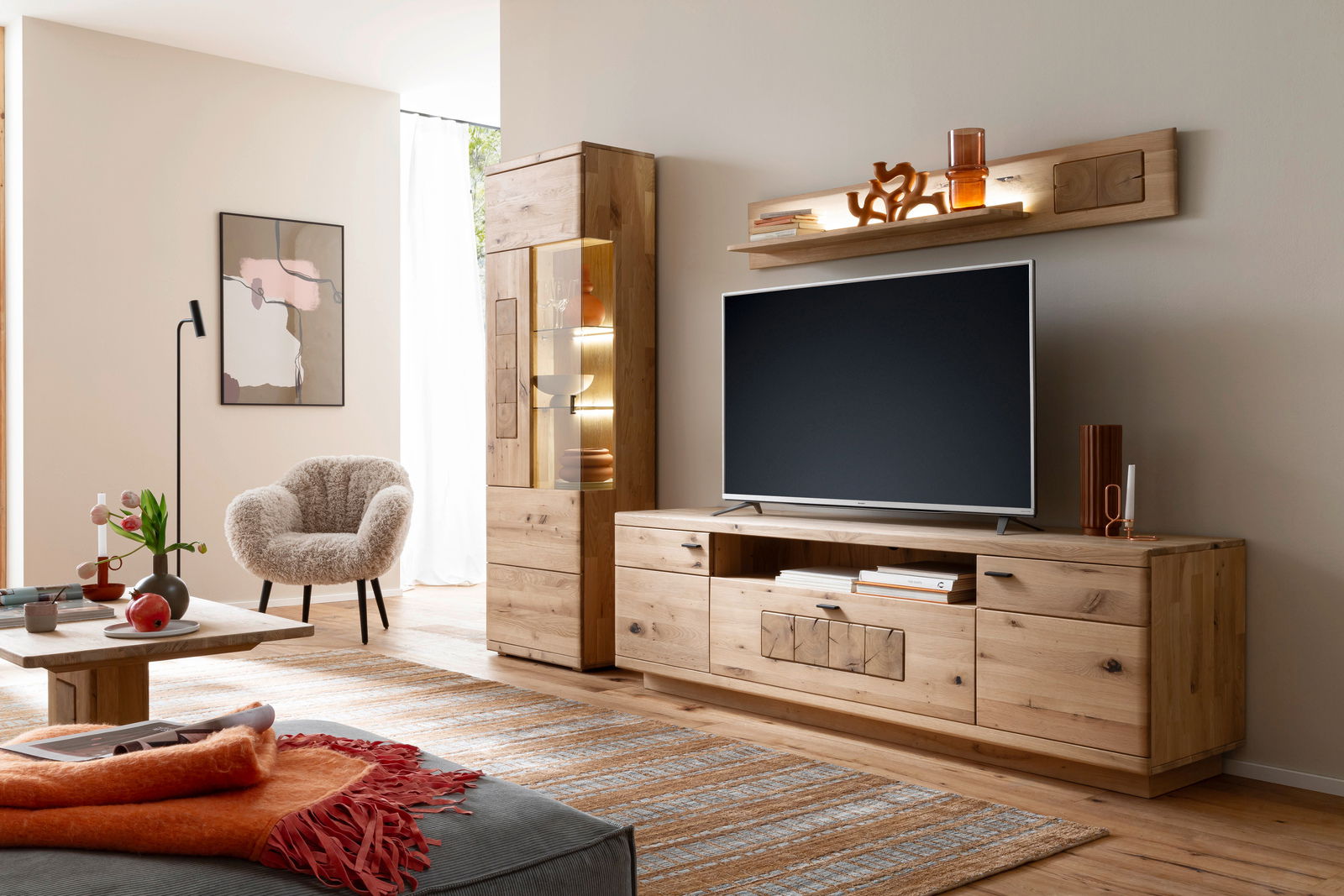 Moderne Wandkombination aus Holz mit TV-Schrank, Vitrine und Wandregal in einem stilvoll eingerichteten Wohnzimmer, seitliche Perspektive.