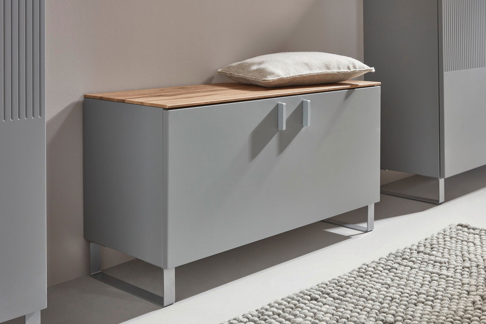 Garderobenbank in modernem Design mit grauer Front und Holzoberfläche, seitliche Perspektive