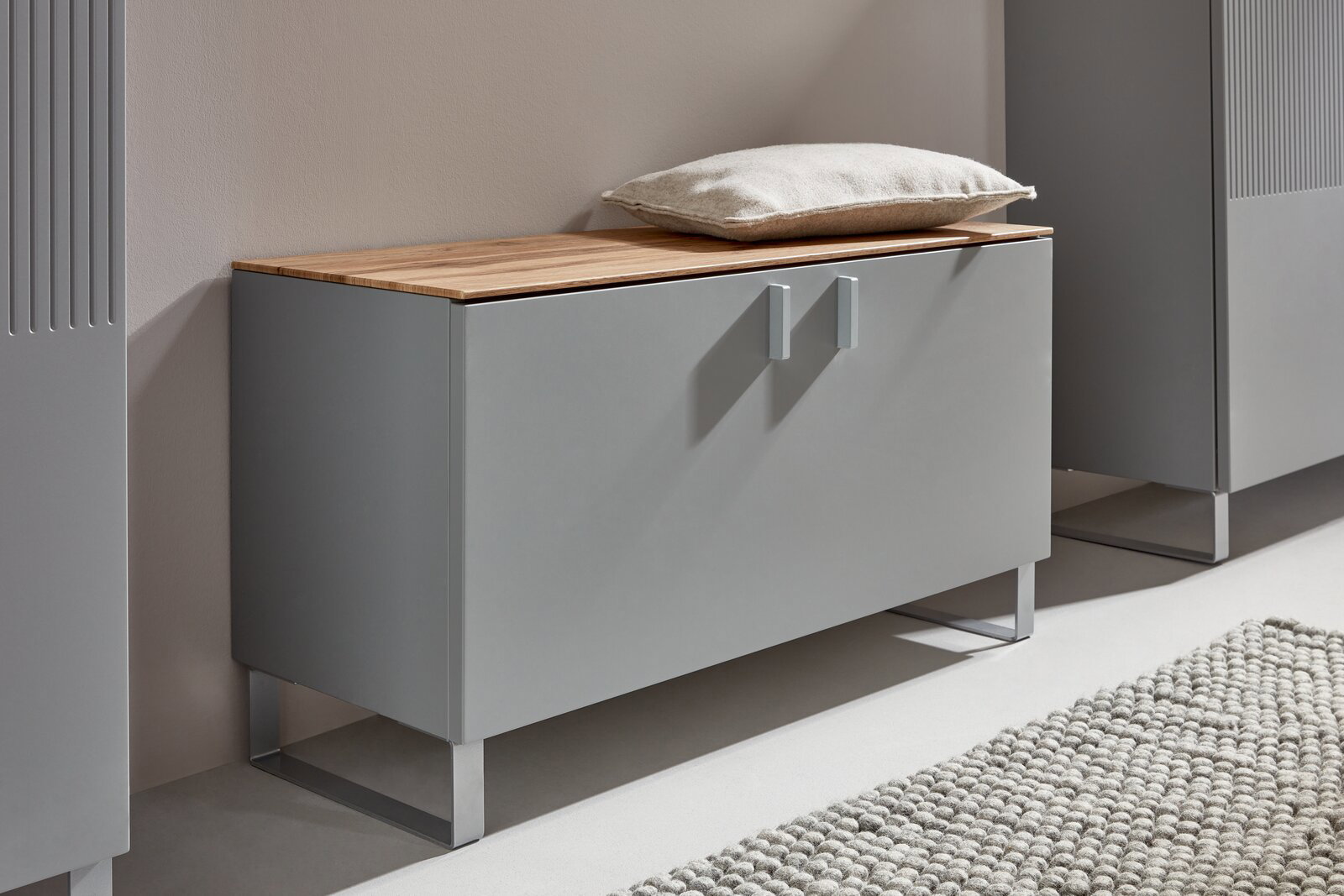 Garderobenbank in modernem Design mit grauer Front und Holzoberfläche, seitliche Perspektive