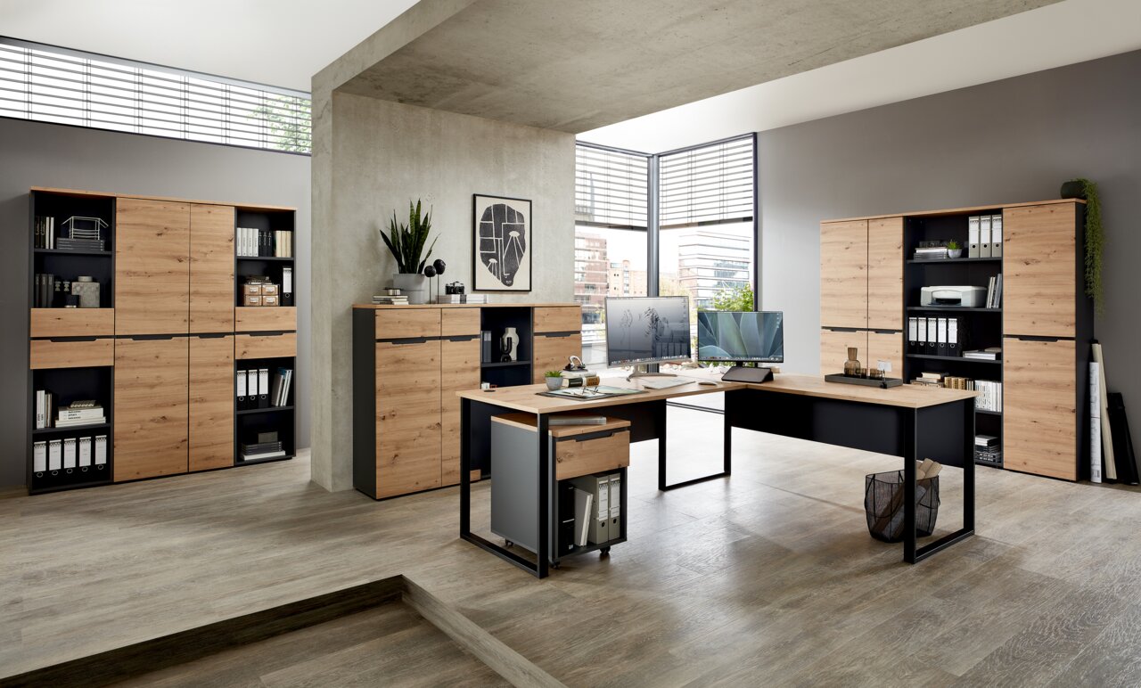 Moderne Büromöbel in einem hellen Raum mit großen Fenstern, bestehend aus Aktenschränken, Regalen und Schreibtischen in Holzoptik. Perspektive von vorne links.