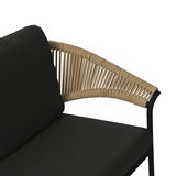 Detailansicht einer Loungegarnitur mit schwarzem Kissen und geflochtenem Armlehnen-Design aus beigem Seil.