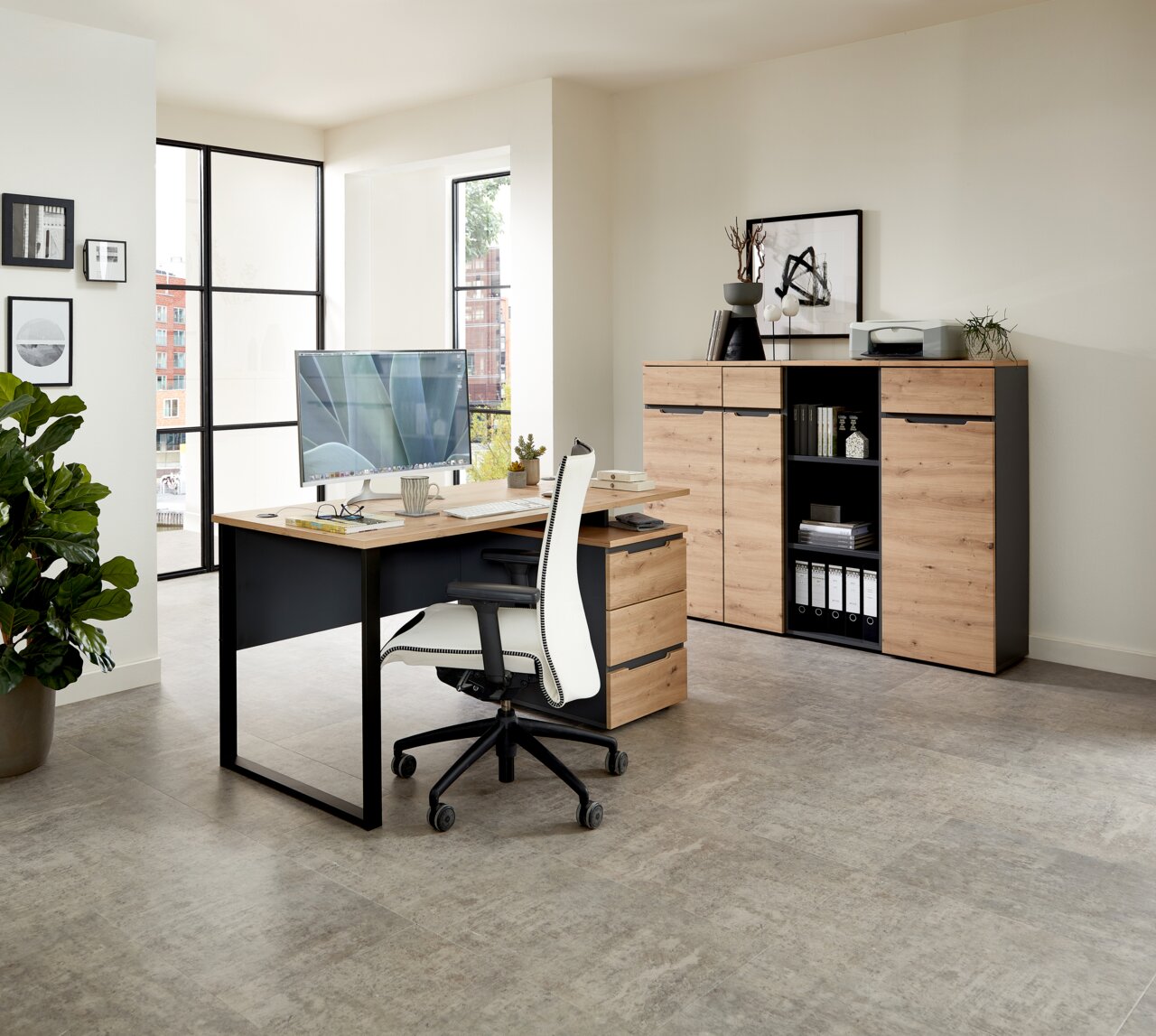 Moderner Schreibtisch mit Holzoberfläche und schwarzem Metallgestell, seitliche Perspektive. Im Hintergrund ein Aktenschrank mit Regalen und Dekorationen.